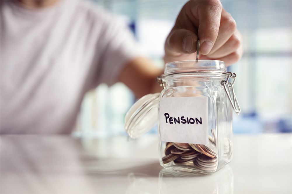 Person wirft Münzen in Glas mit Aufschrift Pension